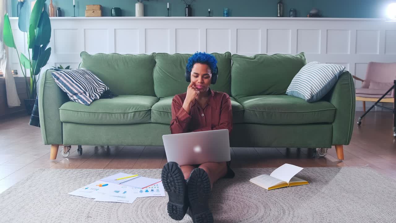 Young pretty african american woman chatting through laptop sits on floor