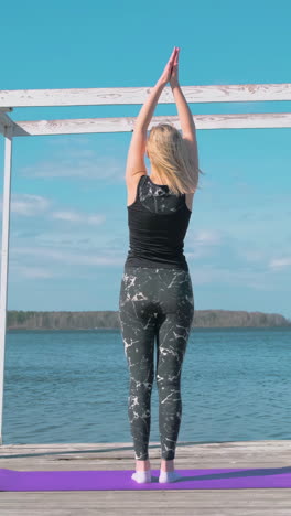 vrouw die buiten bij het meer yoga beoefent