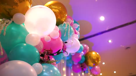 Viele-An-Der-Wand-Befestigte-Luftballons-Sorgen-Für-Eine-Schöne-Formmischung-Aus-Größen-Und-Farben-Auf-Einer-Geburtstagsfeier-Im-Innenbereich-Mit-Lichterketten-In-Zeitlupe