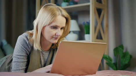 a middle-aged woman uses a laptop on her bed 2