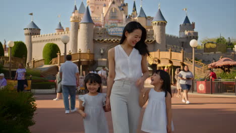family walking through a theme park with a castle in the background