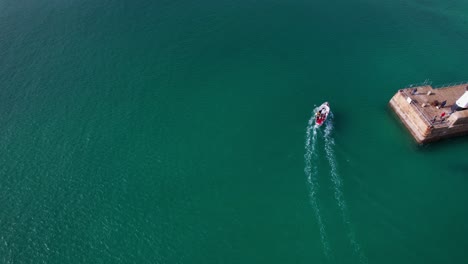 st ives aerial drone view over turquoise harbour in cornwall following a boat with tilt up shot overlooking the coastal town, england, uk