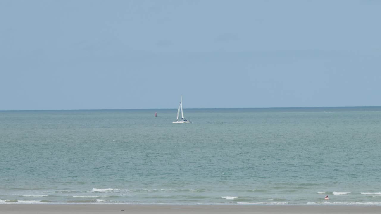 Single sailboat moves steadily on tranquil sea, wide shot, natural daylight, serene summer atmosphere