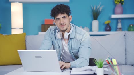 Joven-Estudiante-Universitario-Mirando-A-La-Cámara-Y-Riendo.-Está-Haciendo-Un-Gesto-Positivo.