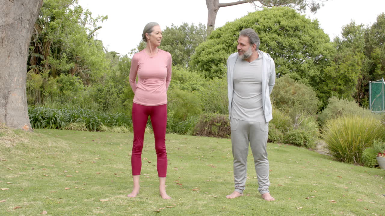Mature couple enjoying outdoor exercise together in peaceful garden setting