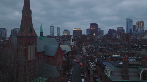 Fly-above-urban-borough-with-houses-and-church-with-red-brick-facades.-Residential-neighbourhood-at-dusk.-Boston,-USA