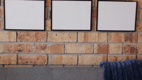 Three-black-frames-and-sofa-with-copy-space-against-brick-wall