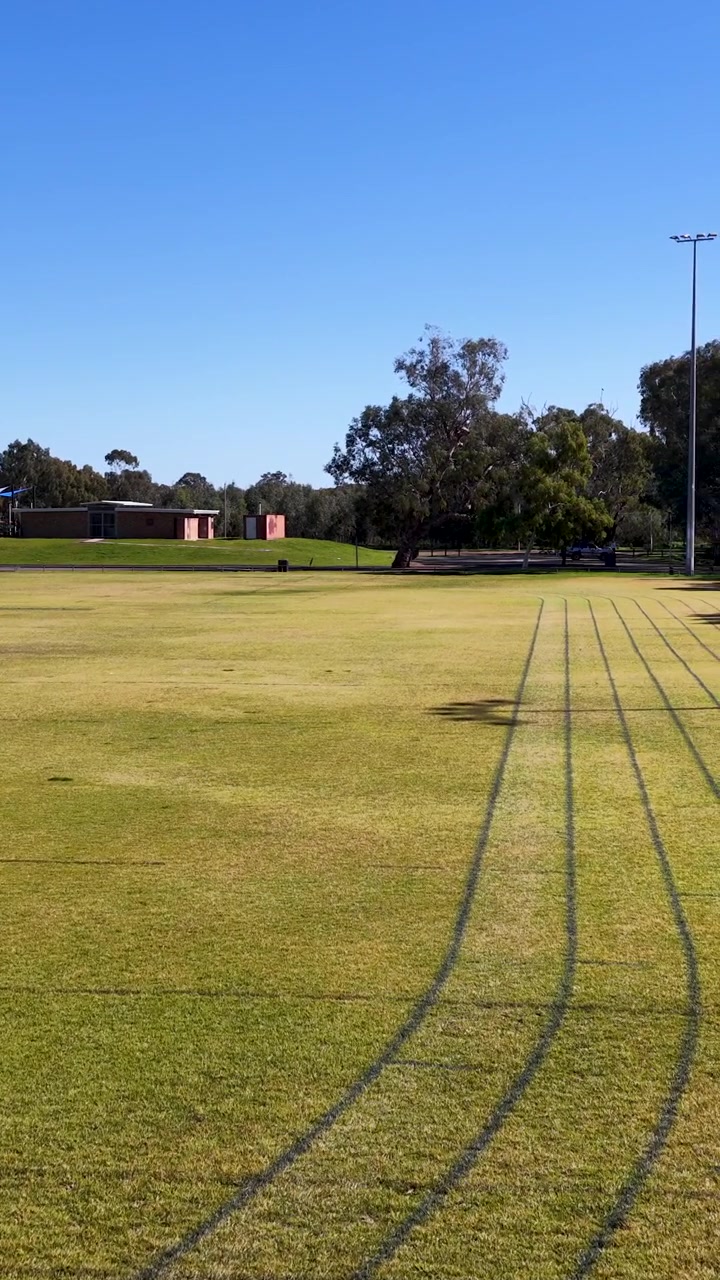 Tomada panorâmica ampla de uma pista de atletismo de grama e um campo esportivo oval em Gunnedah, Austrália.