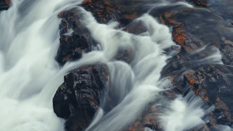 a powerful flow of whitewater over the dark chipped rocks in the long exposure video