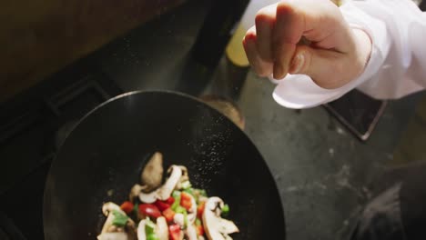 chef añadiendo sal a las verduras