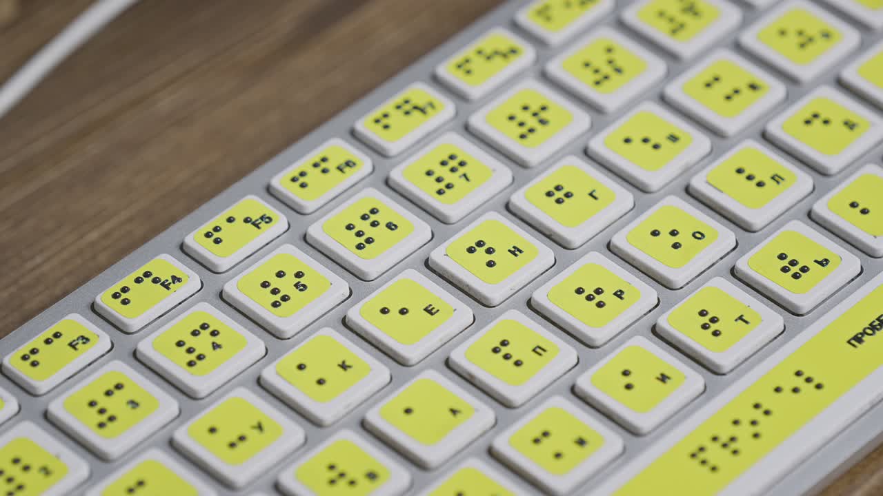 primer plano de un teclado de computadora con braille. una niña ciega está escribiendo palabras en los botones con sus manos.