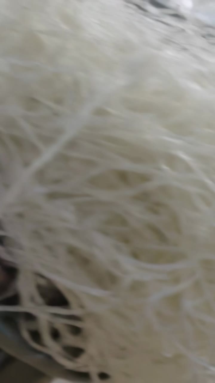 Video verticale: Telecamera che si avvicina su una superficie grigia, mostrando un ciuffo bianco, un perno e un dettaglio di anello scuro.