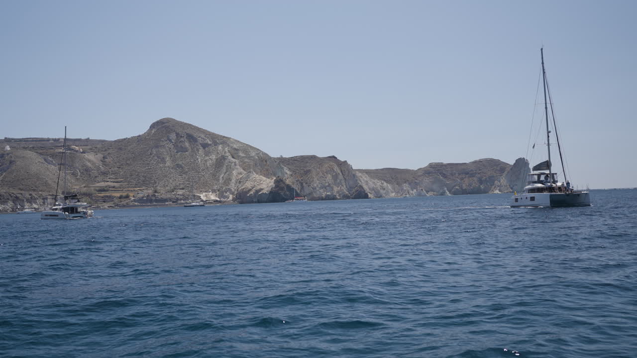 Slow motion shot of boats sailing off of the coast of Santorini in summer