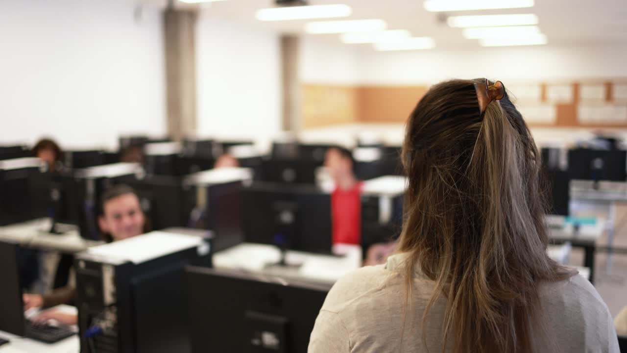 maestro maduro trabajando con estudiantes dentro de la sala de computadoras en la escuela