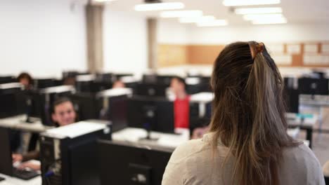 mature teacher working with students inside computer room at school