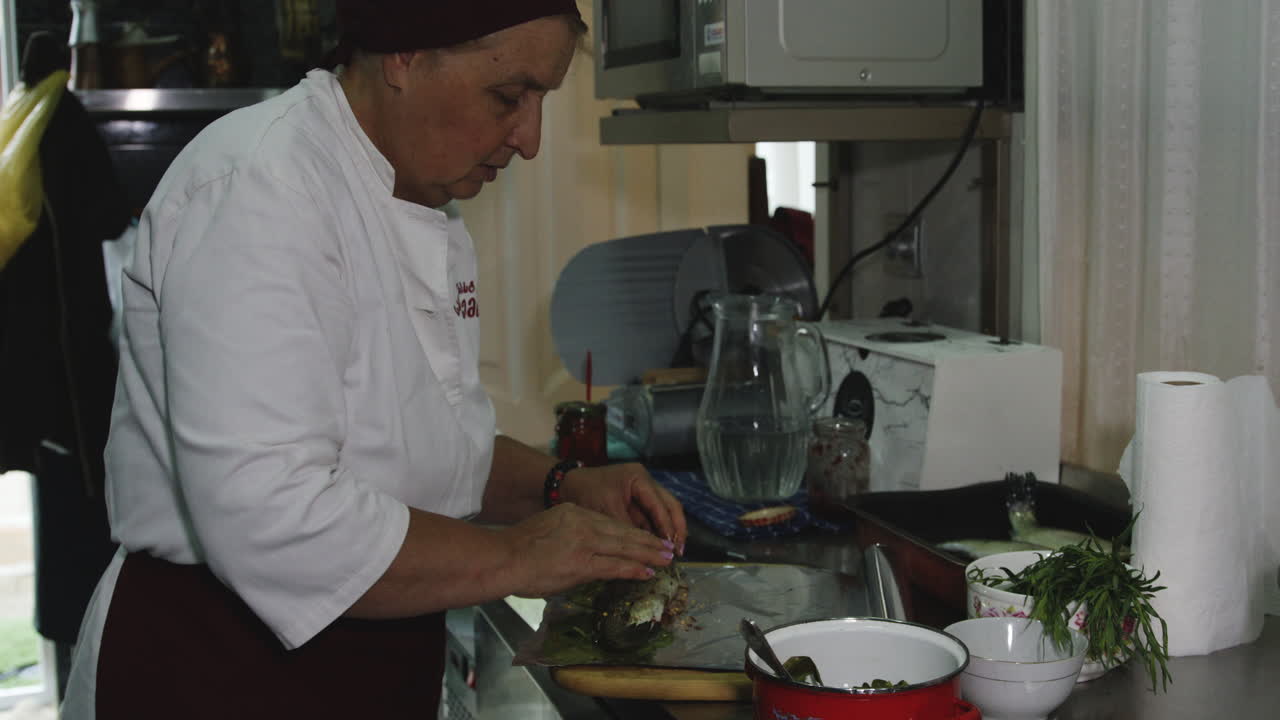 vieja cocinera georgiana condimentando truchas y envolviéndolas en papel de aluminio