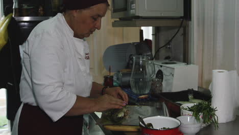 old georgian female chef seasoning trout and wrapping it in tin foil