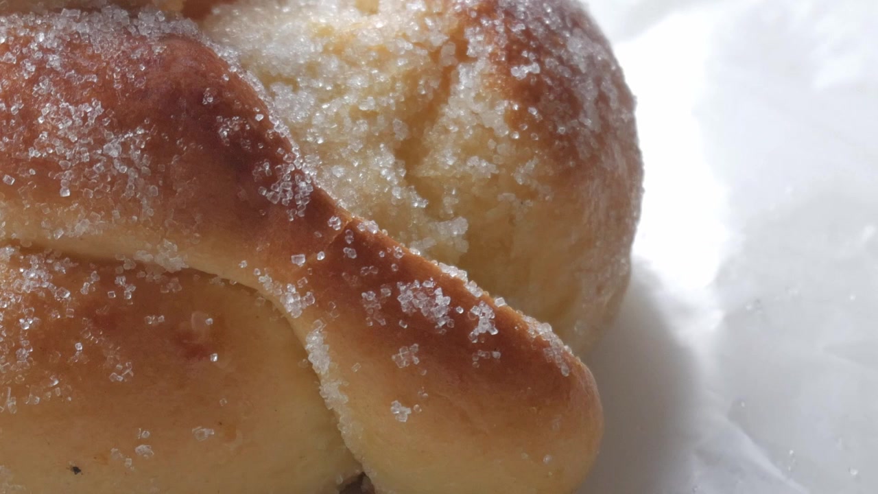 Sweet bread called Bread of the Dead (Pan de Muerto) enjoyed during Day of the Dead festivities in Mexico - closeup slow pan up