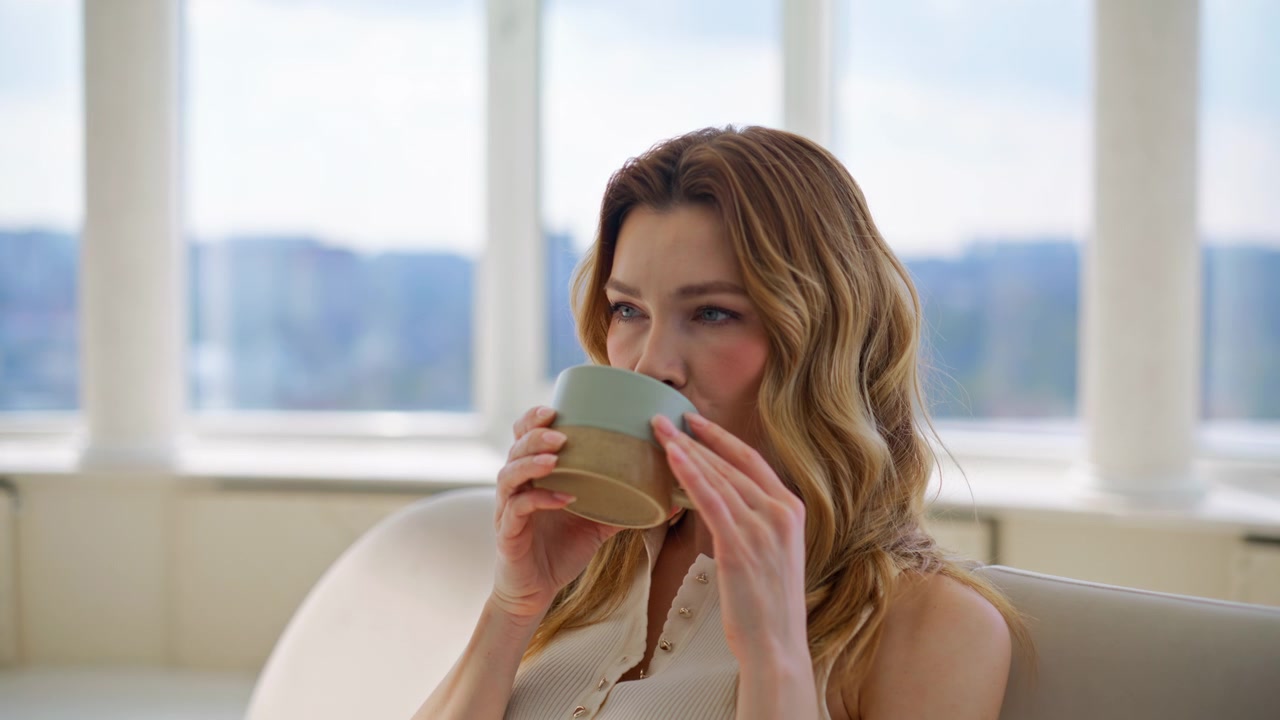 Woman drinking coffee relaxing sofa. Closeup lady enjoying tea home comfort.