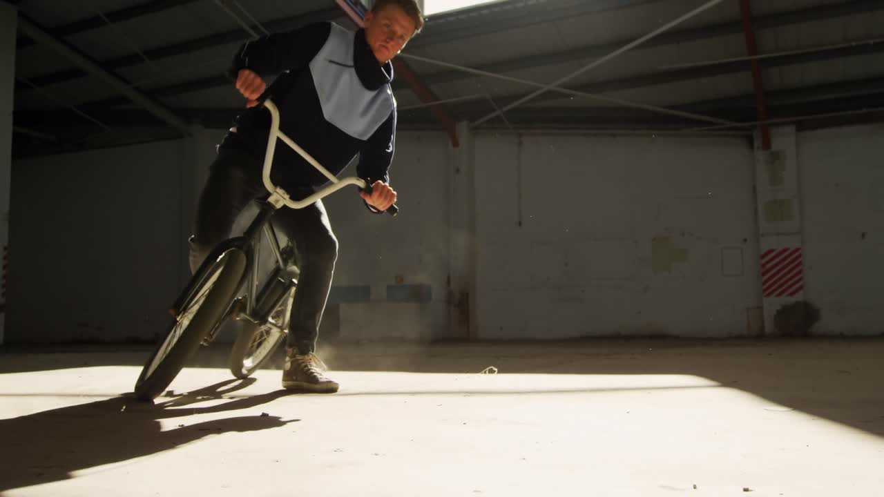 Ciclista BMX in un magazzino vuoto.