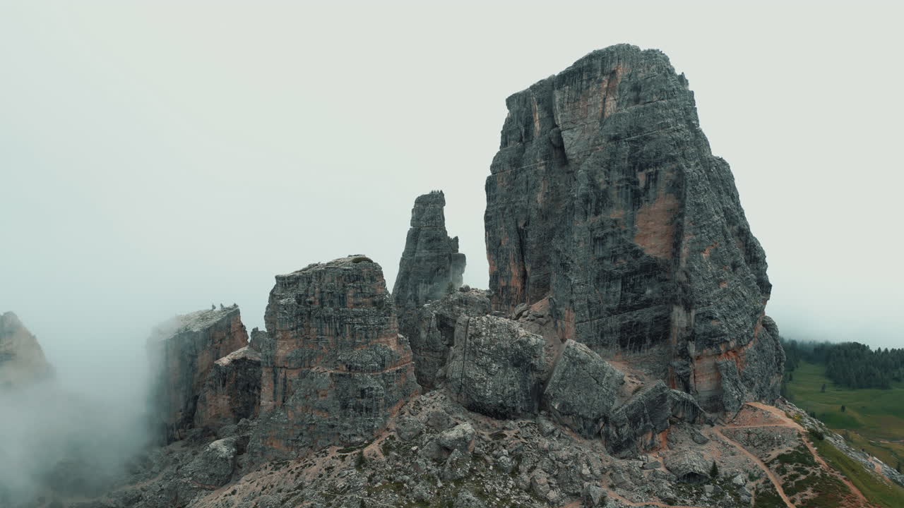 Low clouds rising and revealing Cinque Torri, a group of five rocky peaks in the Dolomites, Italy