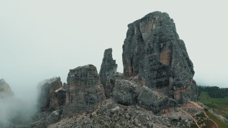 low clouds rising and revealing cinque torri, a group of five rocky peaks in the dolomites, italy