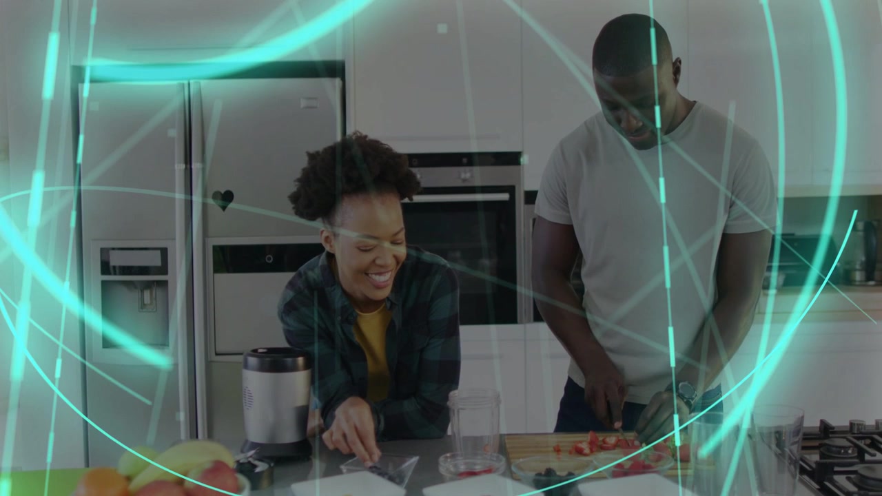 African American couple chopping and laughing while tasting food at kitchen island with chefs knife