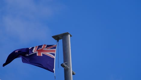 Bandera-De-Nueva-Zelanda-Ondeando-Al-Viento-Con-El-Cielo-Azul-Como-Fondo
