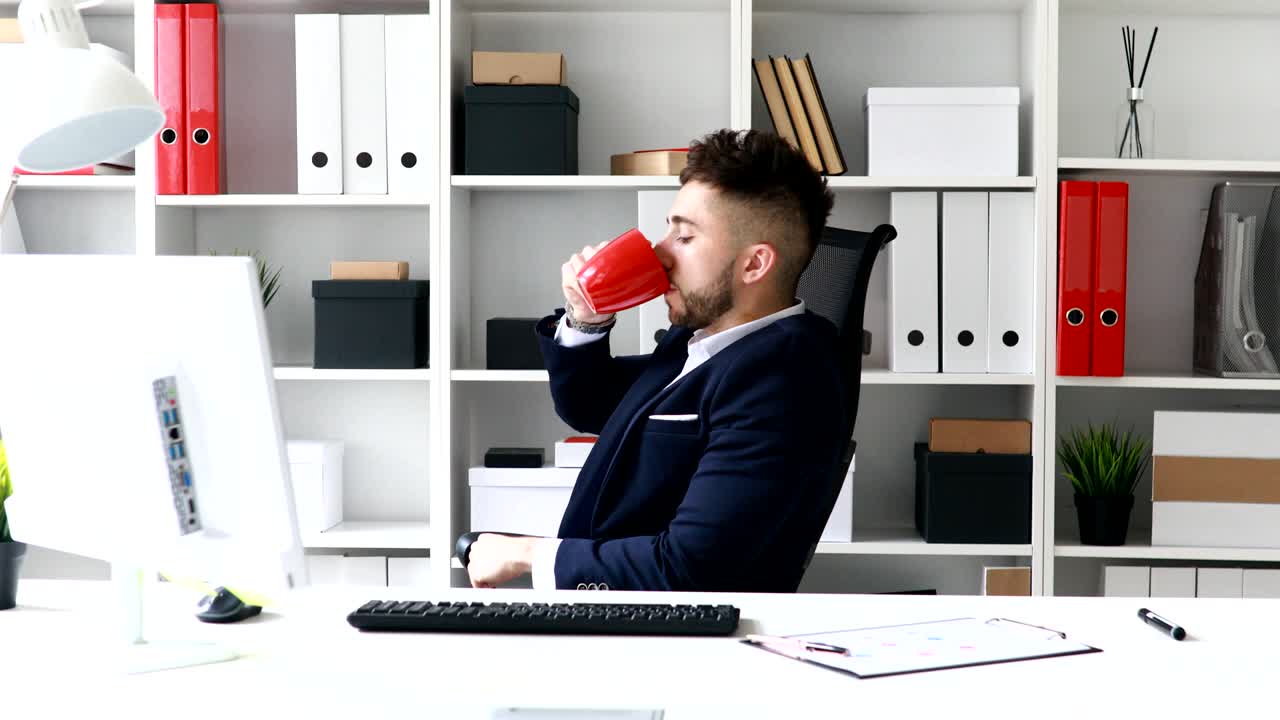 Giovane uomo d'affari che beve caffè sul posto di lavoro.