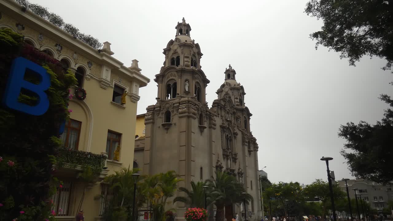 una iglesia o catedral alta llamada "virgen milagrosa" ubicada en lima, peru en el distrito de miraflores muy cerca de un parque publico llamado "parque kennedy"