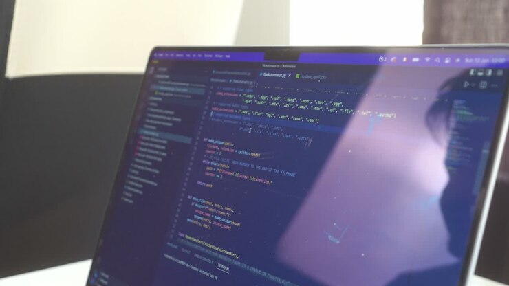 Side view of computer code scrolling back and forth on a reflective laptop computer screen with retina display technology