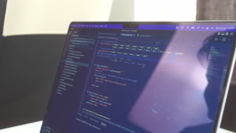 vista lateral del código de computadora que se desplaza hacia adelante y hacia atrás en una pantalla de computadora portátil reflectante con tecnología de pantalla de retina
