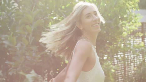 Happy-caucasian-woman-holding-bunch-of-flowers-in-garden-on-sunny-day