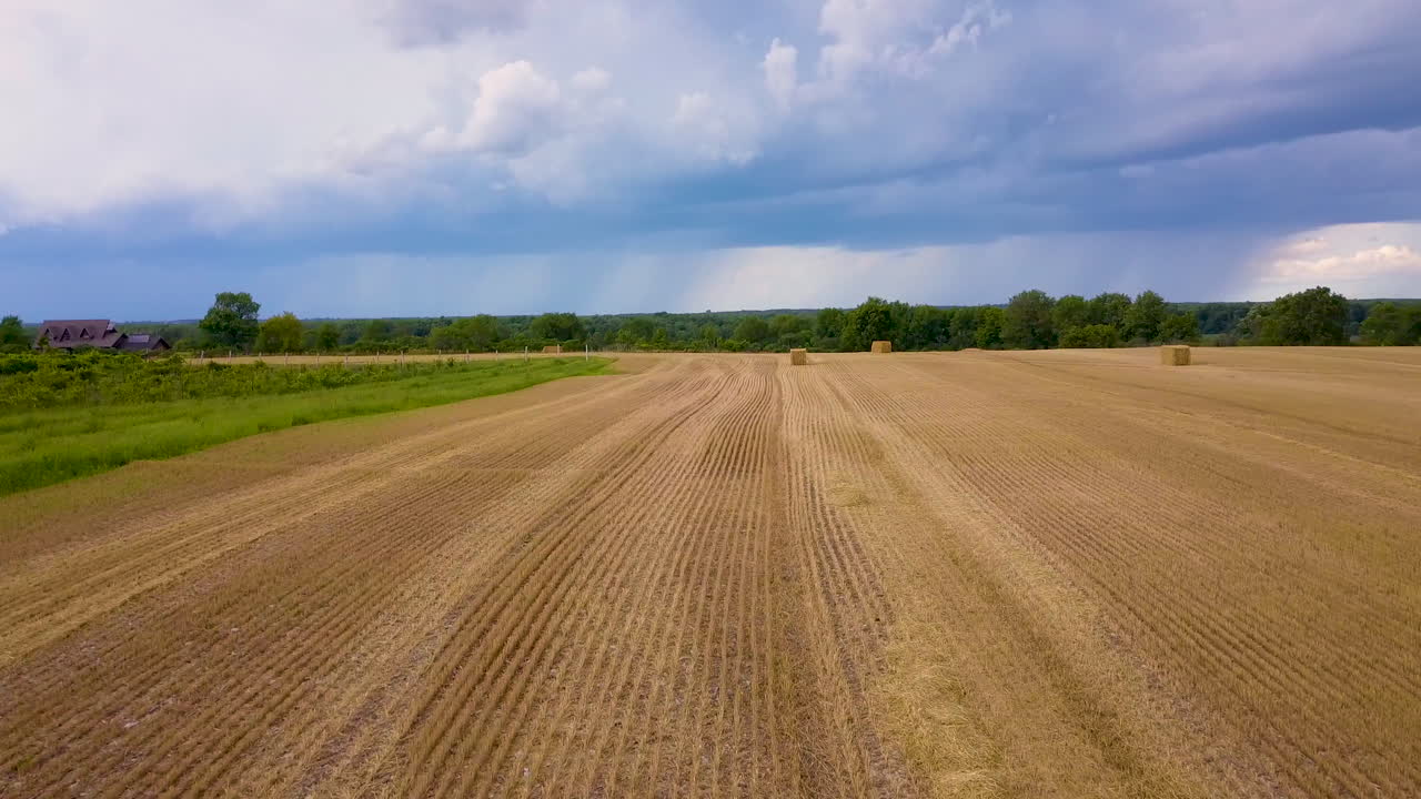 Flug über ein frisch gemähtes Heufeld mit Sturmwolken in der Ferne