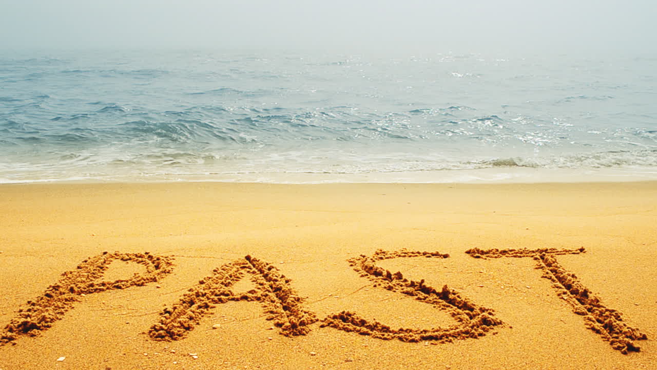 The inscription PAST on a wet sand seacoast. Shooting on the beach