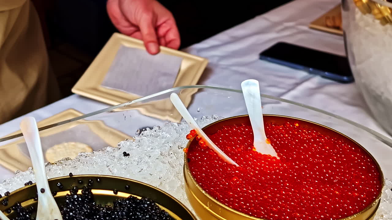 Display of red and black caviar in tins on crushed ice at seafood market