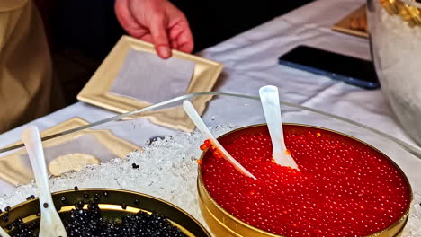 display of red and black caviar in tins on crushed ice at seafood market