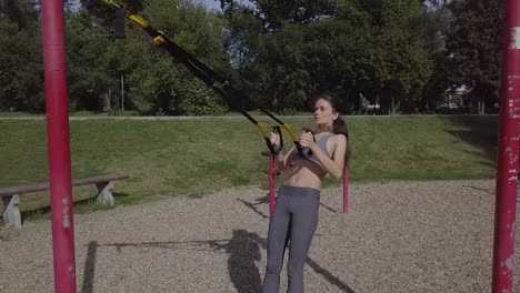 young slim sporty girl doing trx back workout, sporty woman fitness outdoors