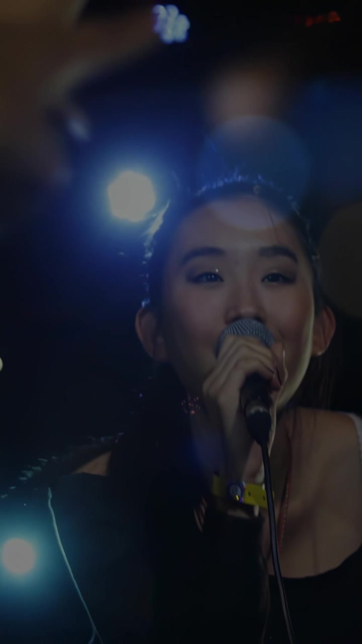 Vertical video: Female singer starting concert, singing into mic, engaging crowd hands and lights