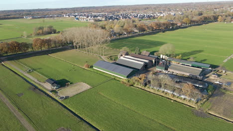 flying towards a farm with solarpanels on roof of barn in rural holland