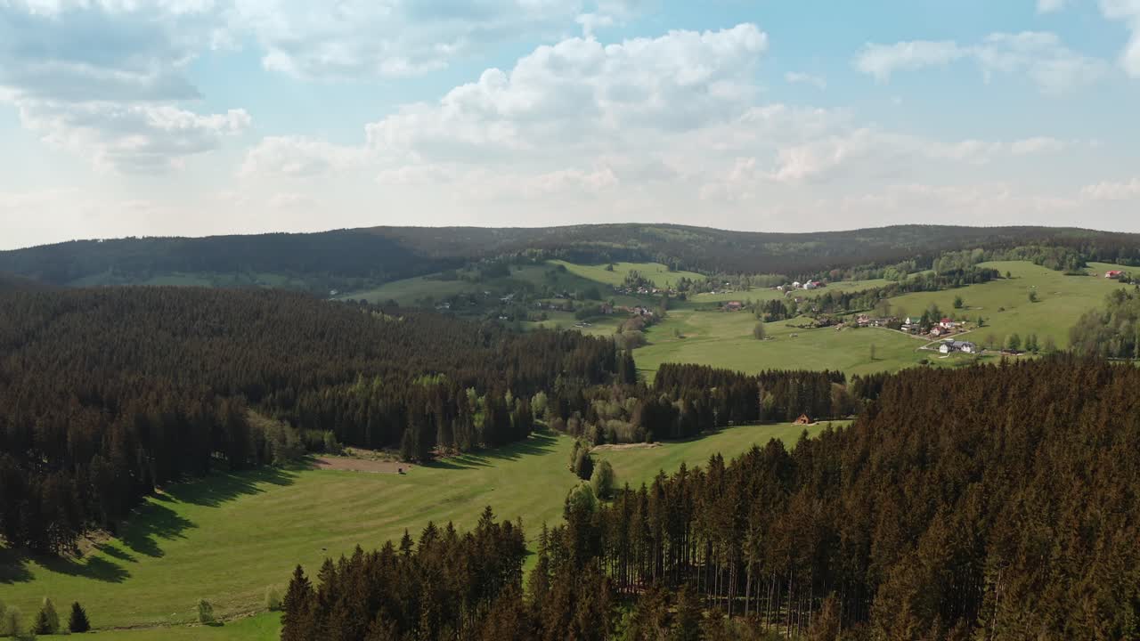 Drone shot of czech highlands village surrounded with spruce forest