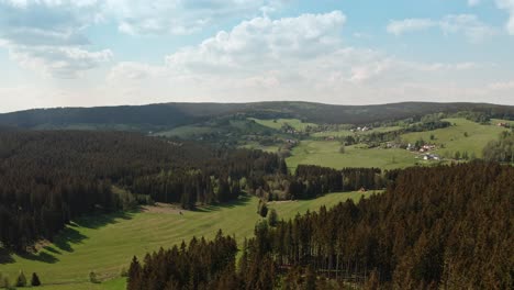 drone shot of czech highlands village surrounded with spruce forest