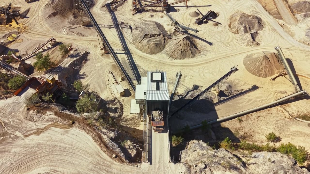 Sand and gravel site with machinery and conveyor belts in operation, captured from above during daylight hours