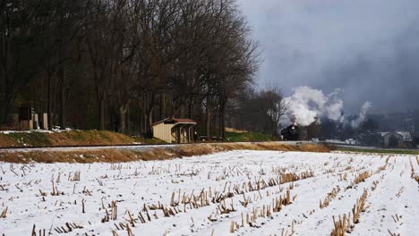 Steam-Engine-and-Passenger-Cars-Puffing-Along-Amish-Farm-Lands-After-the-First-Snow-of-the-Season