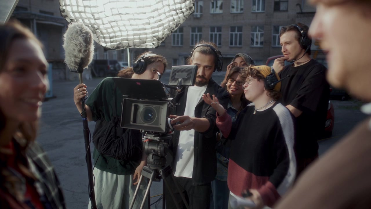 Troupe cinematografica che discute l'inquadratura sul monitor della macchina da presa su un set all'aperto