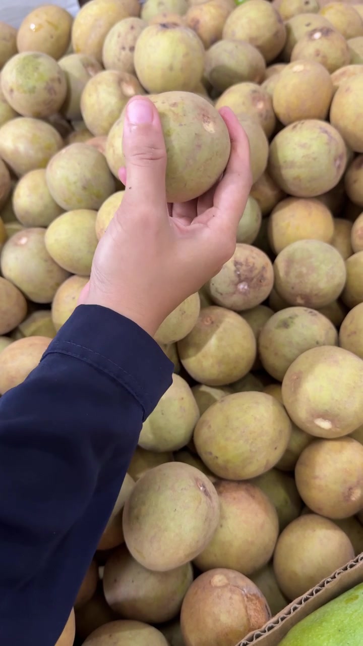 Mano che raccoglie frutto di sapodilla fresco al mercato