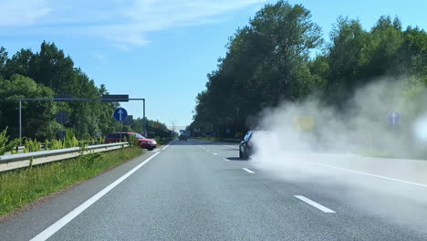 car driving on a highway with white smoke cloud coming from it, captured from behind