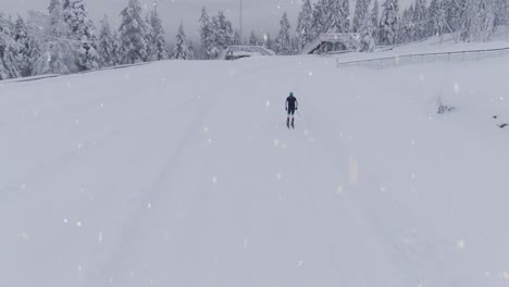 Entrenamiento-De-Esquí-De-Fondo-Durante-Las-Nevadas,-Tiro-Trasero-Aéreo