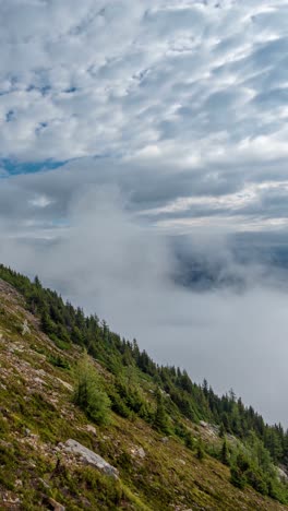 vertical 4k timelapse, clouds and fog moving above mountain peaks and valley