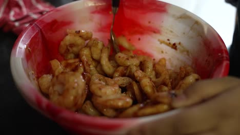 close up shot of hands mixing frozen prawns using spices and oil